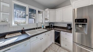 A kitchen with white cabinets, a stainless steel refrigerator, a dishwasher, and a coffee maker.