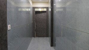 A hallway with glossy grey marble walls and floor, recessed ceiling lights, and a door at the end. - RRA Retreat Hotel (Nathdwara)