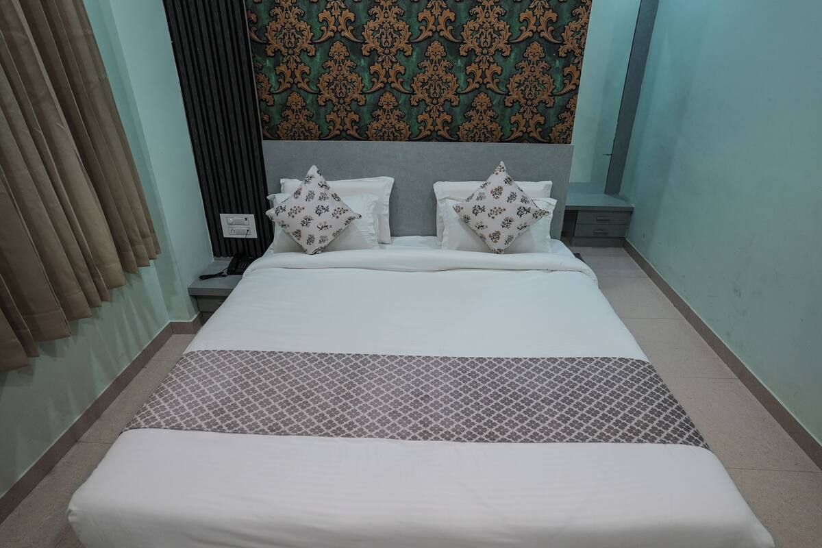 Una habitación de hotel con una cama grande, un cabecero de diseño estampado y una mesita de noche con lámpara.