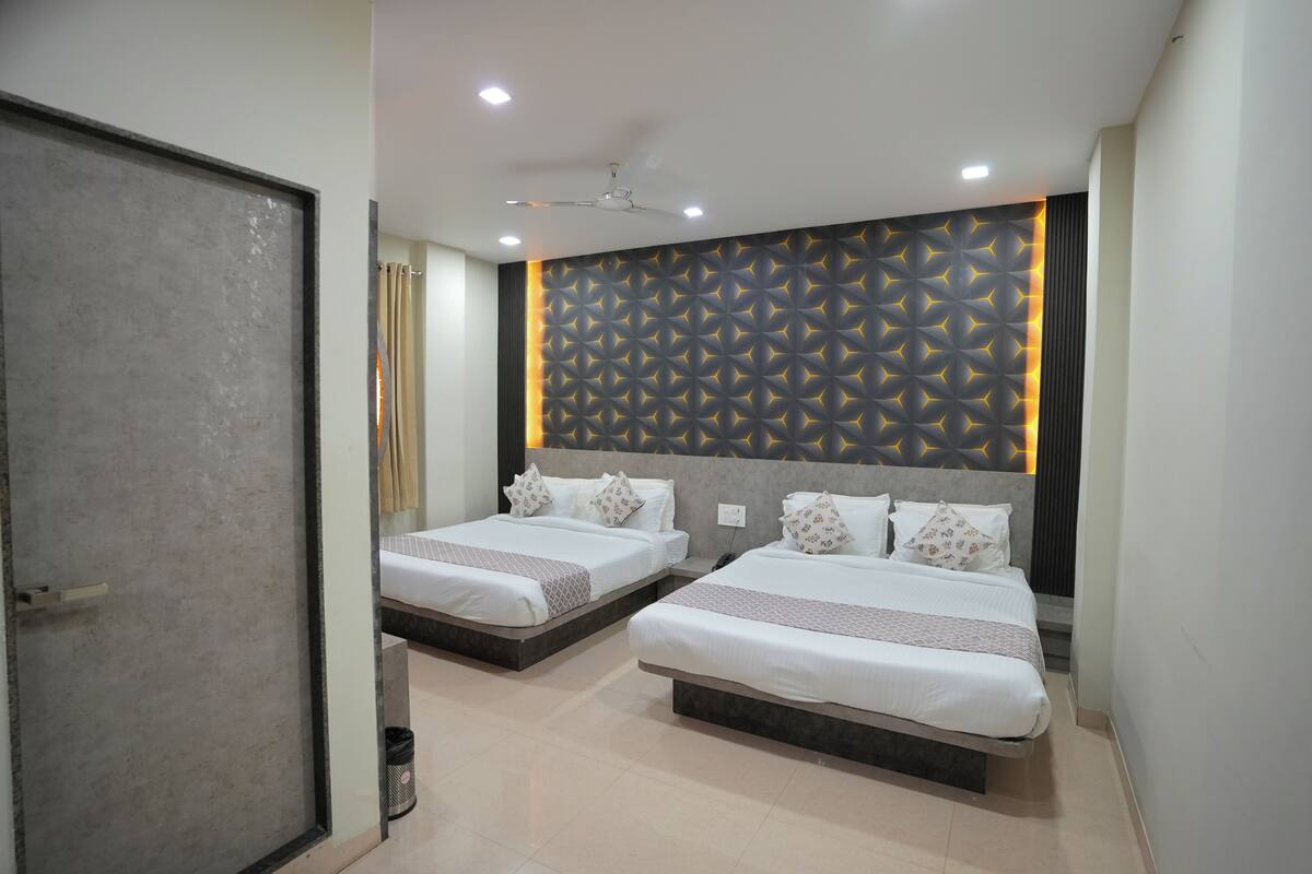 Habitación de hotel con dos camas, ventilador de techo, iluminación empotrada y pared con diseño.