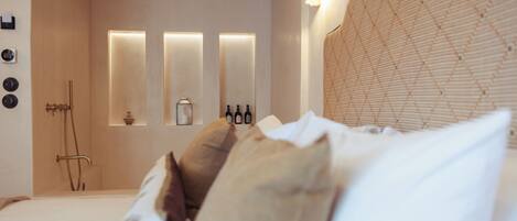 A modern bedroom with a large bed, a headboard with a textured pattern, and a wall-mounted light fixture.