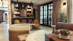 A modern hotel lobby with comfortable seating, a reception desk, and a wall-mounted information board. - Nomad Hotel & Spa Altea (Altea)