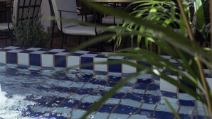 A tiled pool area with chairs and tables, surrounded by plants and a view of the interior. - Nomad Hotel & Spa Altea (Altea)
