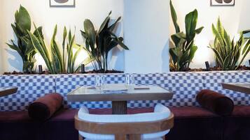 A modern interior with a checkered bench, a round wooden table, and potted plants.
