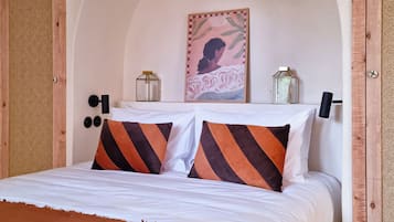 A bedroom with a large bed, a wooden headboard, a wall arch, and a painting.