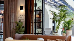 A modern living area with a brown sofa, two wicker chairs, a round table, and a hanging light fixture. - Nomad Hotel & Spa Altea (Altea)