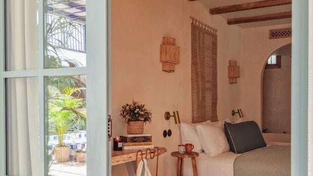 A bedroom with a bed, a desk with a chair, a small table with a cup, and a window with curtains. - Nomad Hotel & Spa Altea (Altea)
