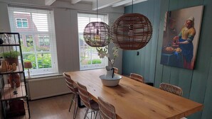 Un coin repas avec une table en bois, des chaises en osier et des lampes en osier suspendues au plafond.