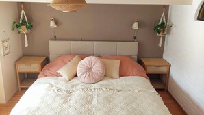 Une chambre à coucher comprenant un lit, deux tables de chevet, un luminaire suspendu et des lampes fixées au mur.