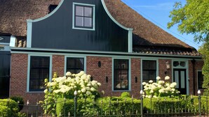 Une maison traditionnelle avec un toit à forte pente, une cheminée centrale et une petite fenêtre.