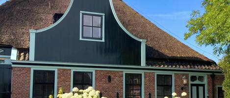 A traditional house with a steeply pitched roof, a central chimney, and a small window.