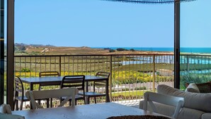 Un balcone con vista sul mare, un tavolo e delle sedie.