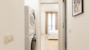 A hotel room with a washing machine, a bed, and a framed picture on the wall. - notaMi - Campus Bligny Bocconi District (Milan)