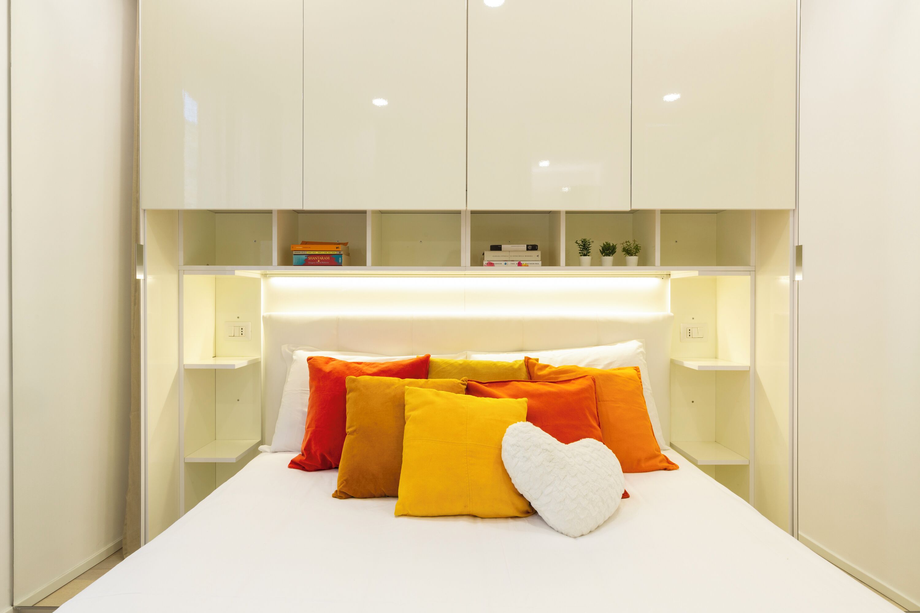 Een moderne slaapkamer met een bed, een wit hoofdeinde en nachtkastjes.