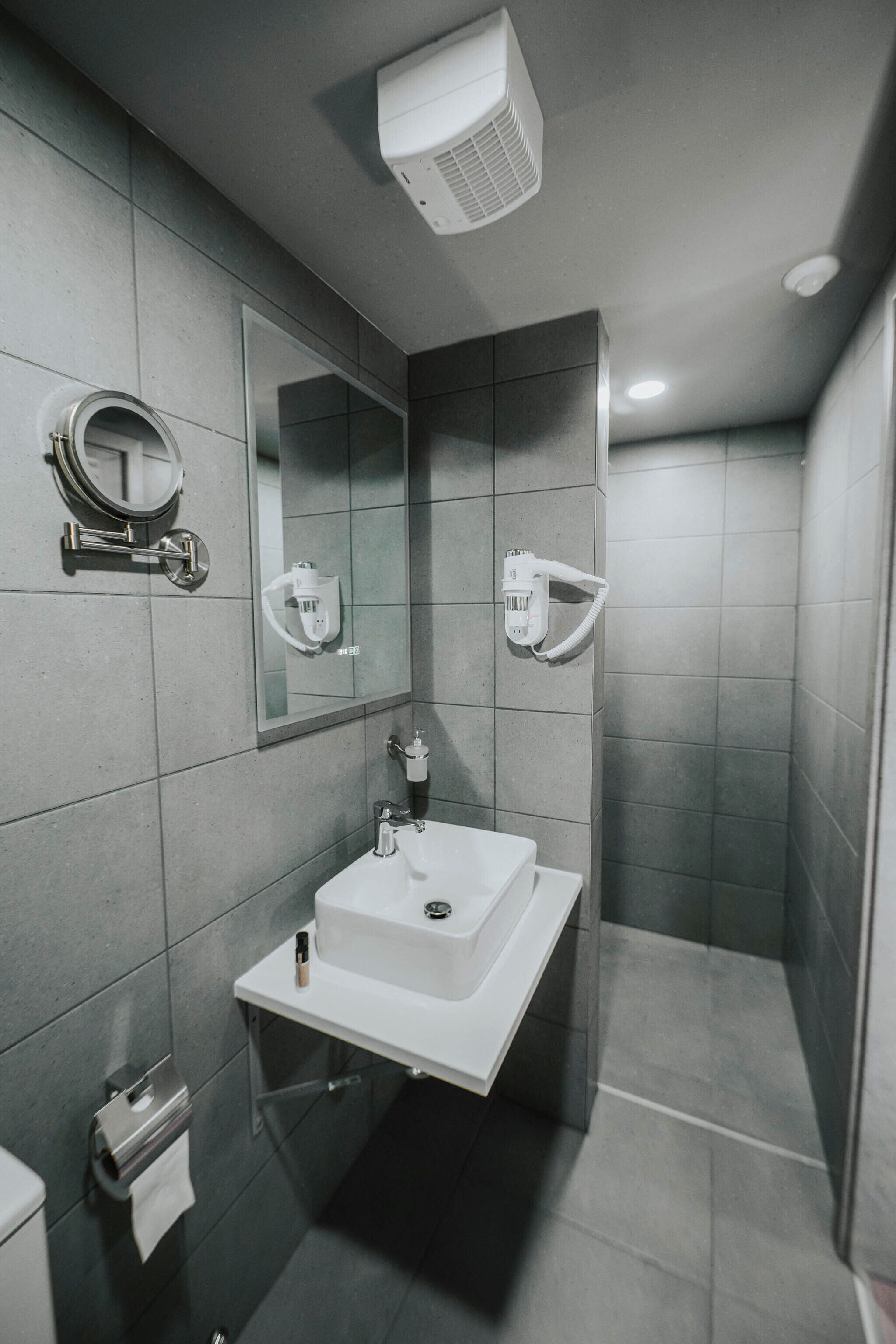 Ein modernes Badezimmer mit Waschbecken, Spiegel und Handtuchspender.