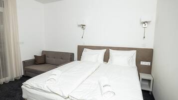 Una camera d'albergo con un letto, un divano e due luci a parete.