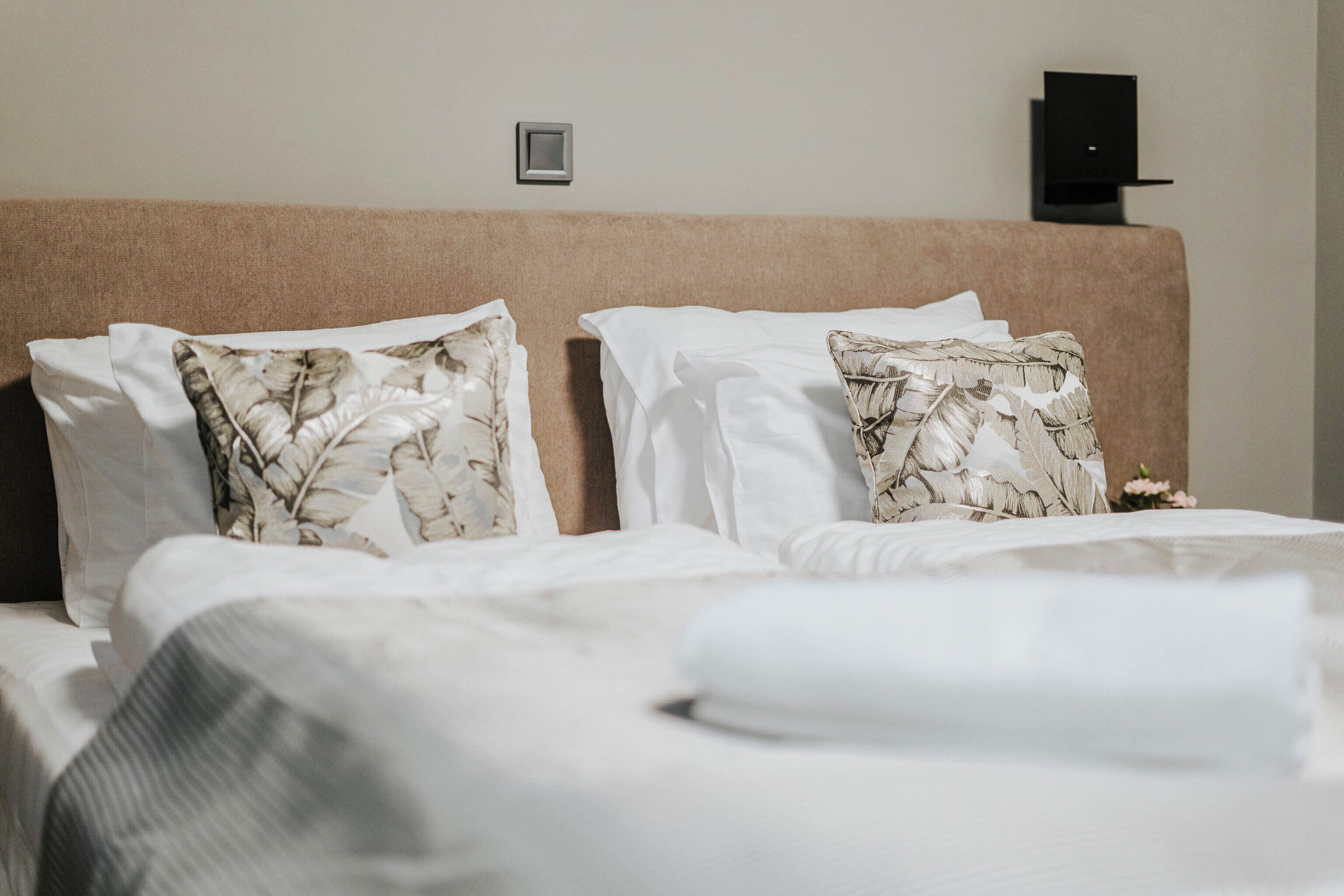 A neatly made bed with floral-patterned pillows and a white comforter.
