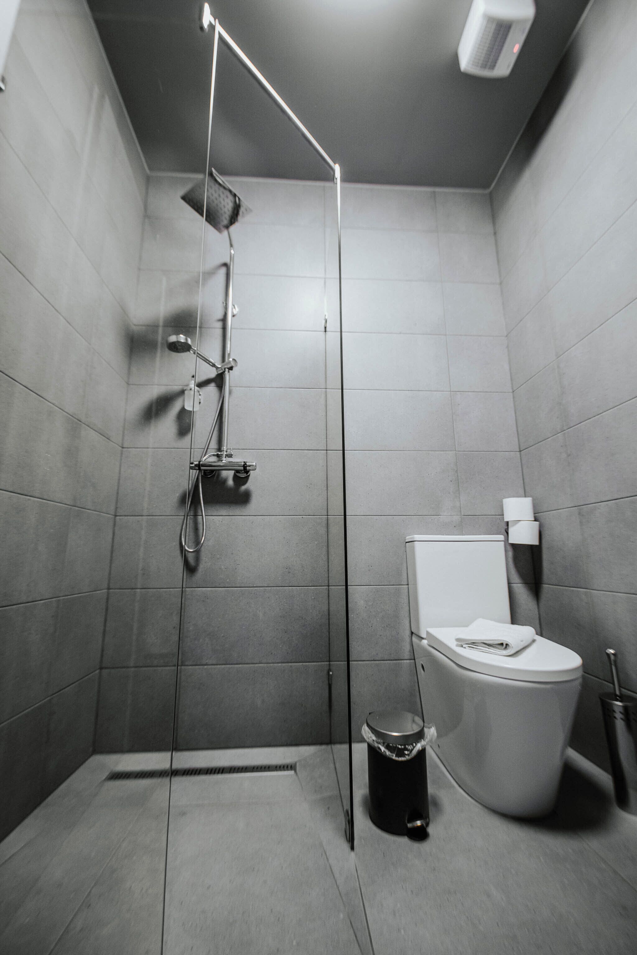 Une salle de bain moderne équipée d’une douche, de toilettes et d’une poubelle.