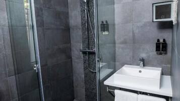 A modern bathroom with a glass-enclosed shower, a white sink, and a towel rack.