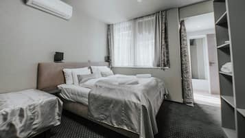 Hotelkamer met een bed, nachtkastje, airconditioning, raam met gordijnen en een kledingkast.
