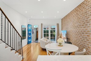 Staircase leads to an upper level, with a dining area and brick wall.