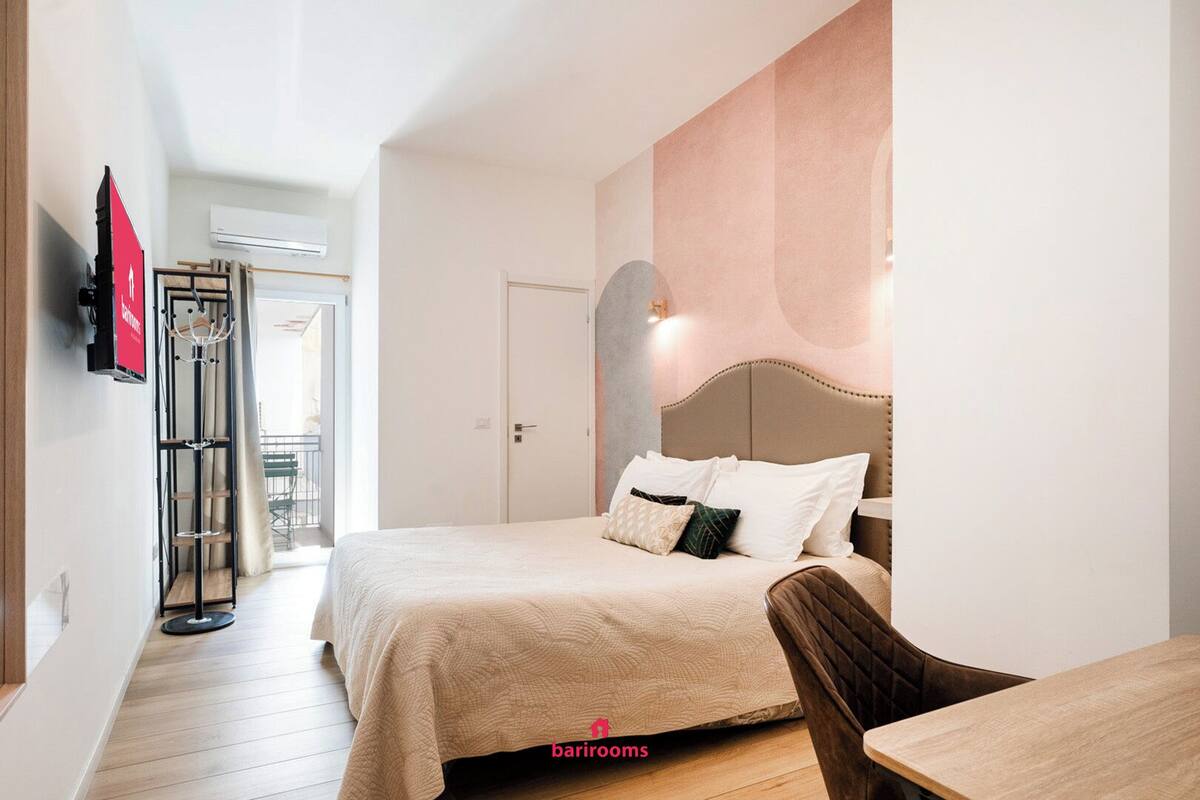 Ein Hotelzimmer mit einem Bett, einem Sessel, einem Tisch und einem an der Wand befestigten Fernseher.