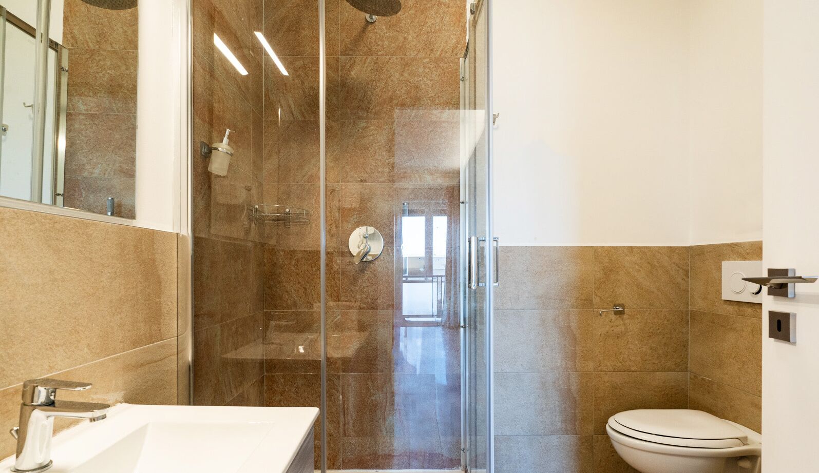 A modern bathroom with a glass-enclosed shower, a white sink, and a toilet.