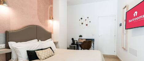 Una camera d'albergo con un letto grande, una scrivania e una TV appesa al muro.