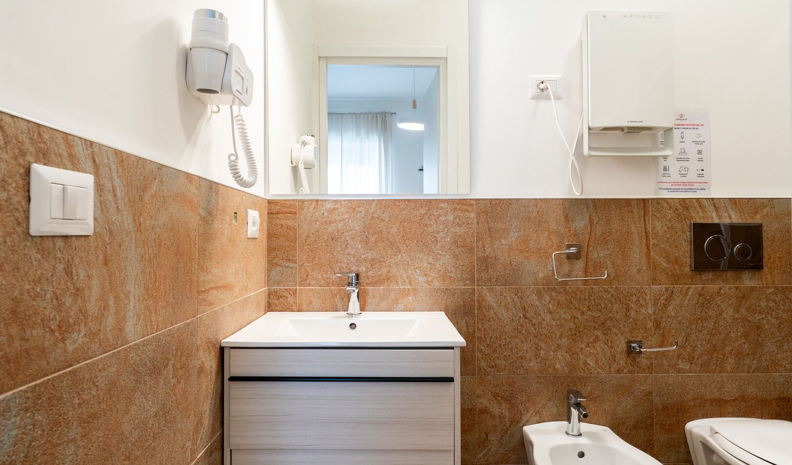 Een badkamer met een wastafel, spiegel, handdoekhouder en toilet.