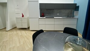 A compact kitchen with white cabinets, a black countertop, and a small refrigerator.
