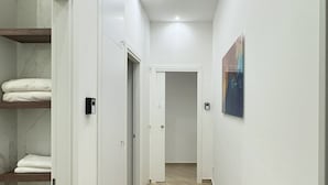 A modern, well-lit hallway with a wooden floor, white walls, and a door leading to another room.