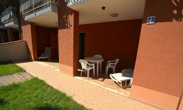A small outdoor patio area with a table and chairs, a door, and a number '23' on the wall. - Comfy Beachside Vacation Home With Patio and Garden (Lignano Sabbiadoro)