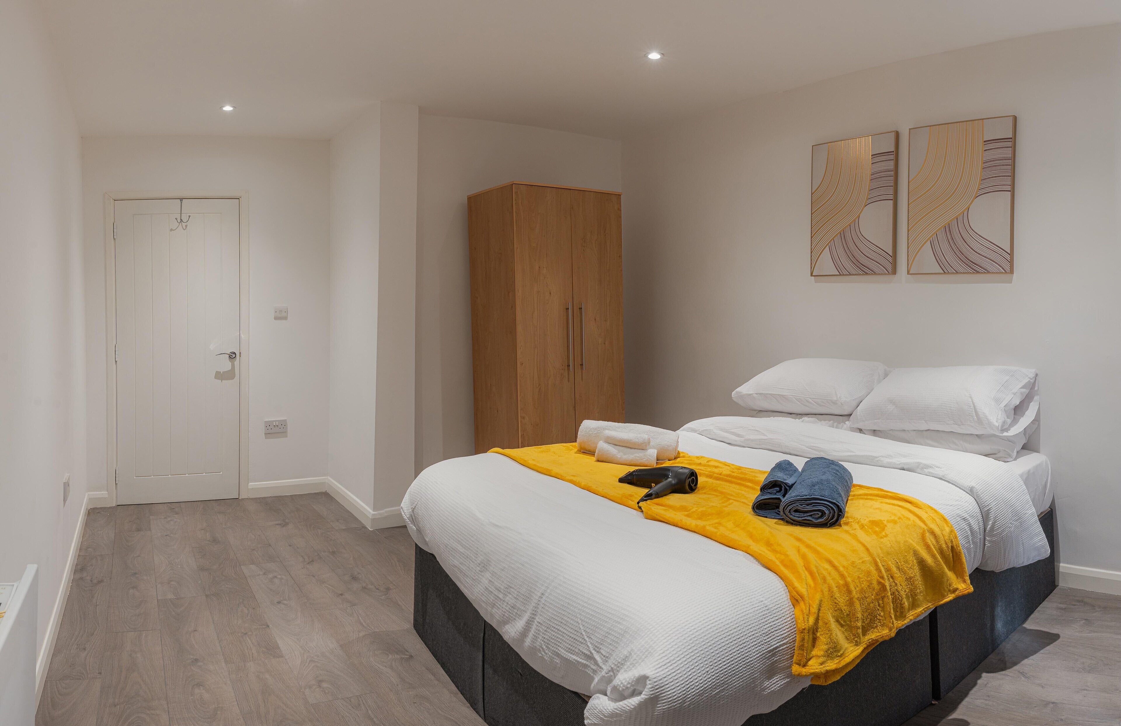A bedroom with a bed, a wardrobe, and two wall-mounted artworks.