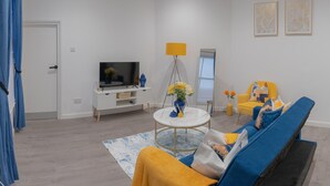 En moderne stue med sofa, sofabord, fjernsyn og lampe.