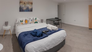 Et moderne soveværelse med en stor seng, et skrivebord og en stol.