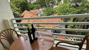 Un balcon avec une table et des chaises, une bouteille de vin et un verre.