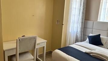 Un dormitorio con una cama, un escritorio y una silla.