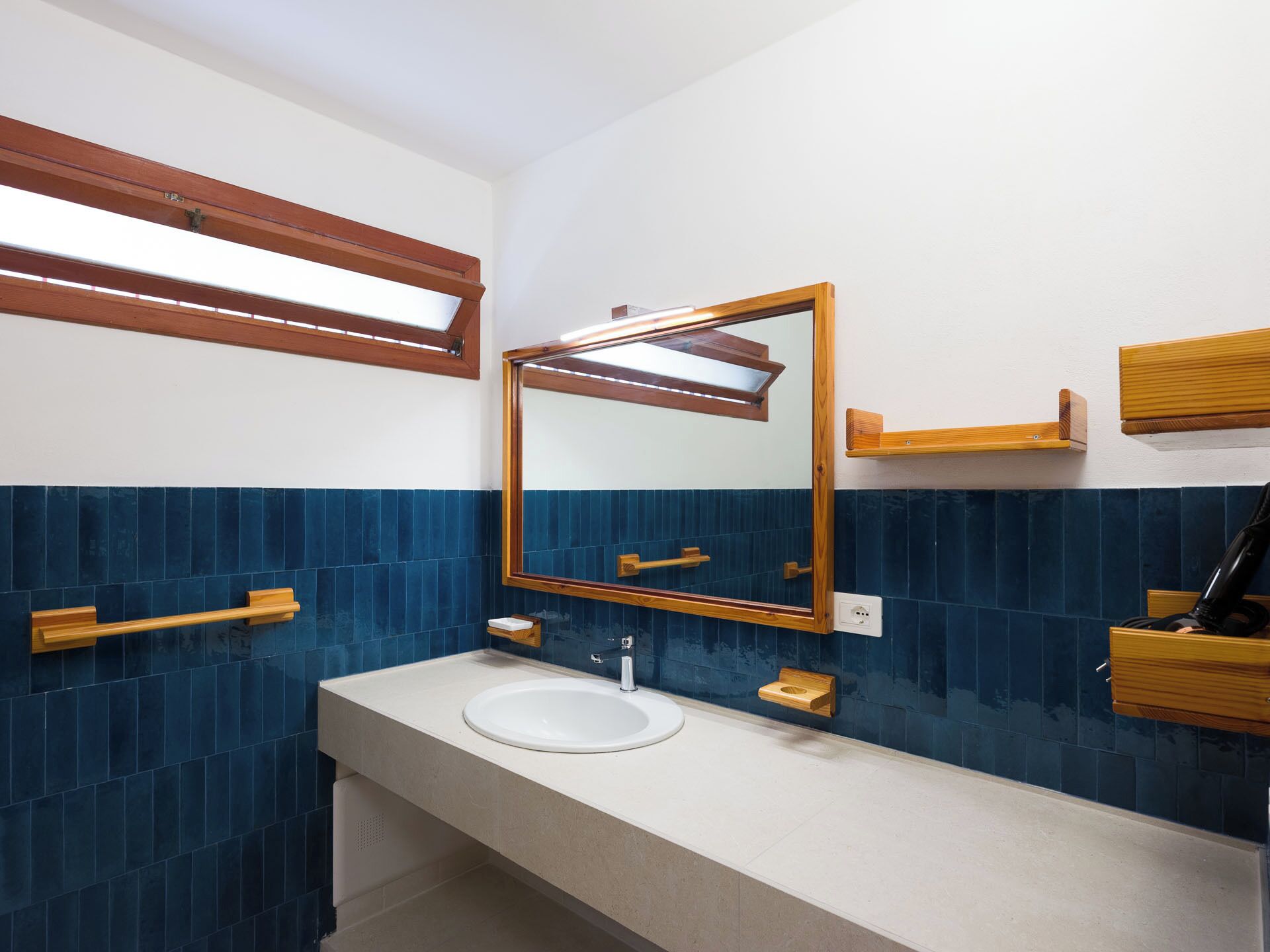 A bathroom with a white sink, a mirror, and wooden shelves.