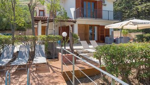 Ein zweistöckiges Haus mit Balkon, Außenbereich zum Sitzen und einem Pool.
