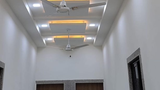 Una habitació amb un disseny de sostre modern, amb il·luminació empotrada i un ventilador central.