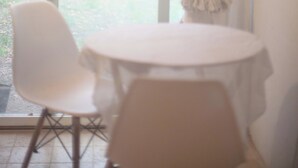A room with a round table and two chairs, a window with curtains, and a view of greenery outside. - Terre libre 2, glamping. Hutt with garden and access to a river. (Fayence)