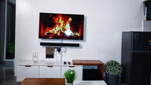 A modern kitchen with a flat-screen TV mounted on the wall, a white countertop, a wooden table, and a black refrigerator. - Comfort home! made life simple, Beautiful views and desirable lifestyle. (Nairobi)