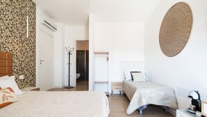 Une chambre d’hôtel avec deux lits, un dressing, une salle de bain et un élément décoratif mural.