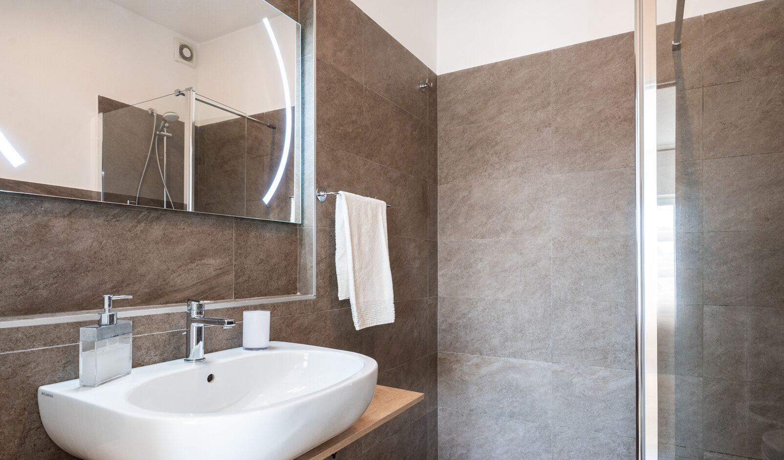 A modern bathroom with a white sink, a mirror, and a glass shower enclosure.