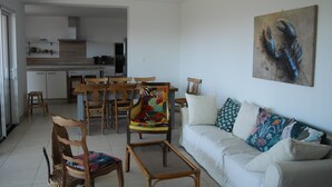 Una sala de estar moderna con un sofá, sillas y un comedor con mesa y sillas.