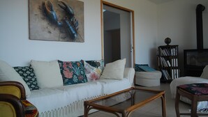 Un salón con un sofá blanco, una mesa de centro de madera, una estantería y un cuadro en la pared.