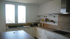 Una cocina moderna con una isla grande, armarios blancos y un ventanal que proporciona luz natural.