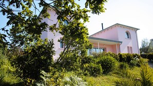 Un edificio rosa con un jardín delantero.