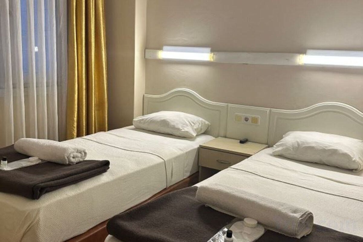 Ein Hotelzimmer mit zwei Einzelbetten, einem Nachttisch und einer Nachttischlampe.