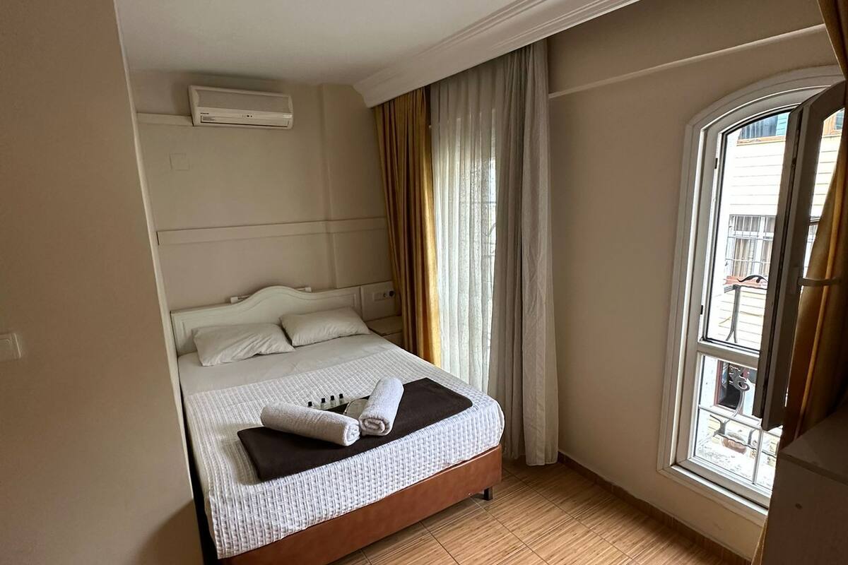 A hotel room with a bed, a window, and a view of the outside.